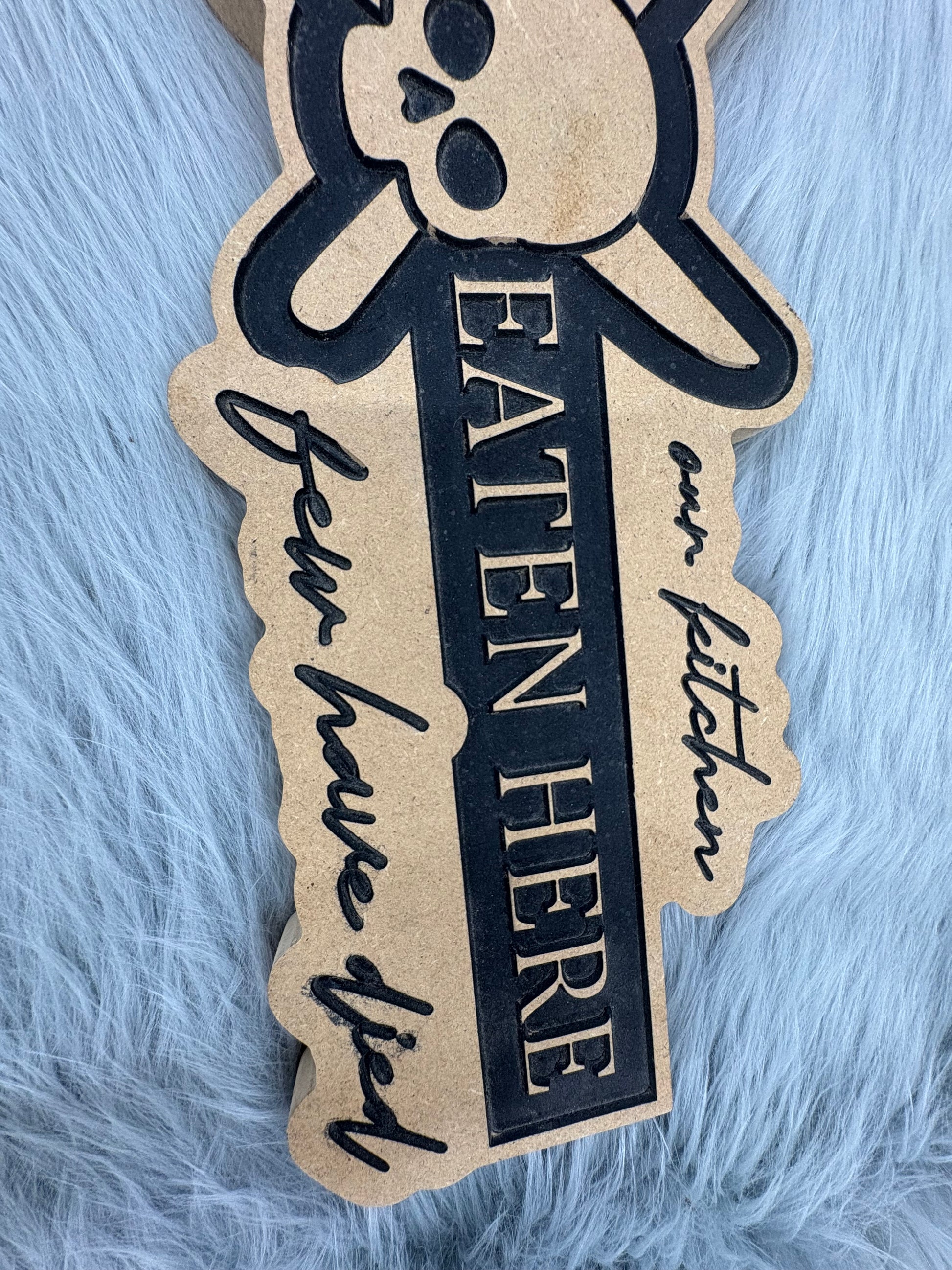 CNC Engraved Kitchen Sign – “Welcome to Our Kitchen: Many Have Eaten Here, Few Have Died” with Skull & Crossbones | Rustic Black & Wood Look | 9.5” x 16” | $30