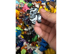 Hand holding a zebra figurine over a collection of colorful animal figurines.
