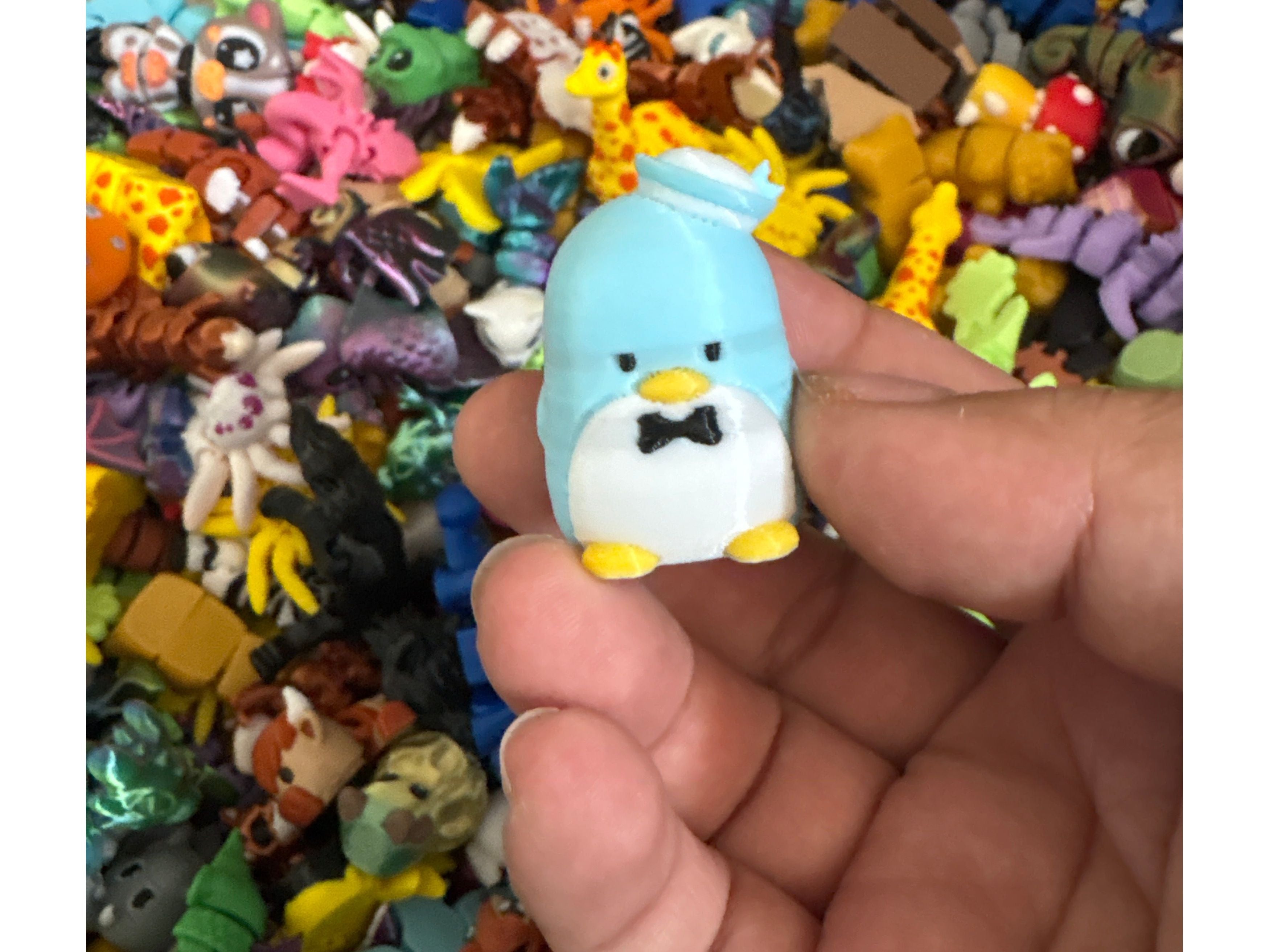 Hand holding a small blue and white figurine with colorful background of various toys