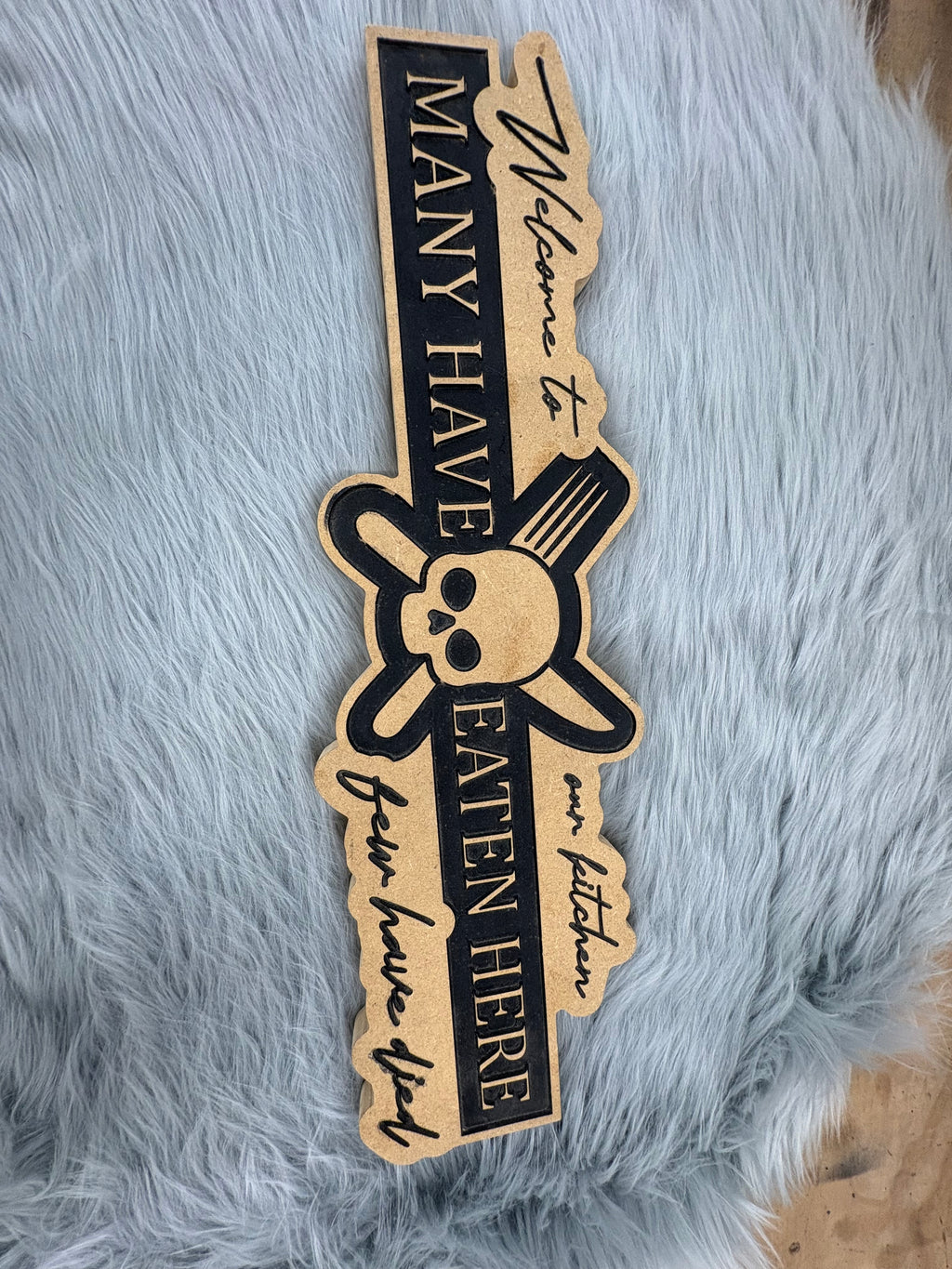 CNC Engraved Kitchen Sign – “Welcome to Our Kitchen: Many Have Eaten Here, Few Have Died” with Skull & Crossbones | Rustic Black & Wood Look | 9.5” x 16” | $30