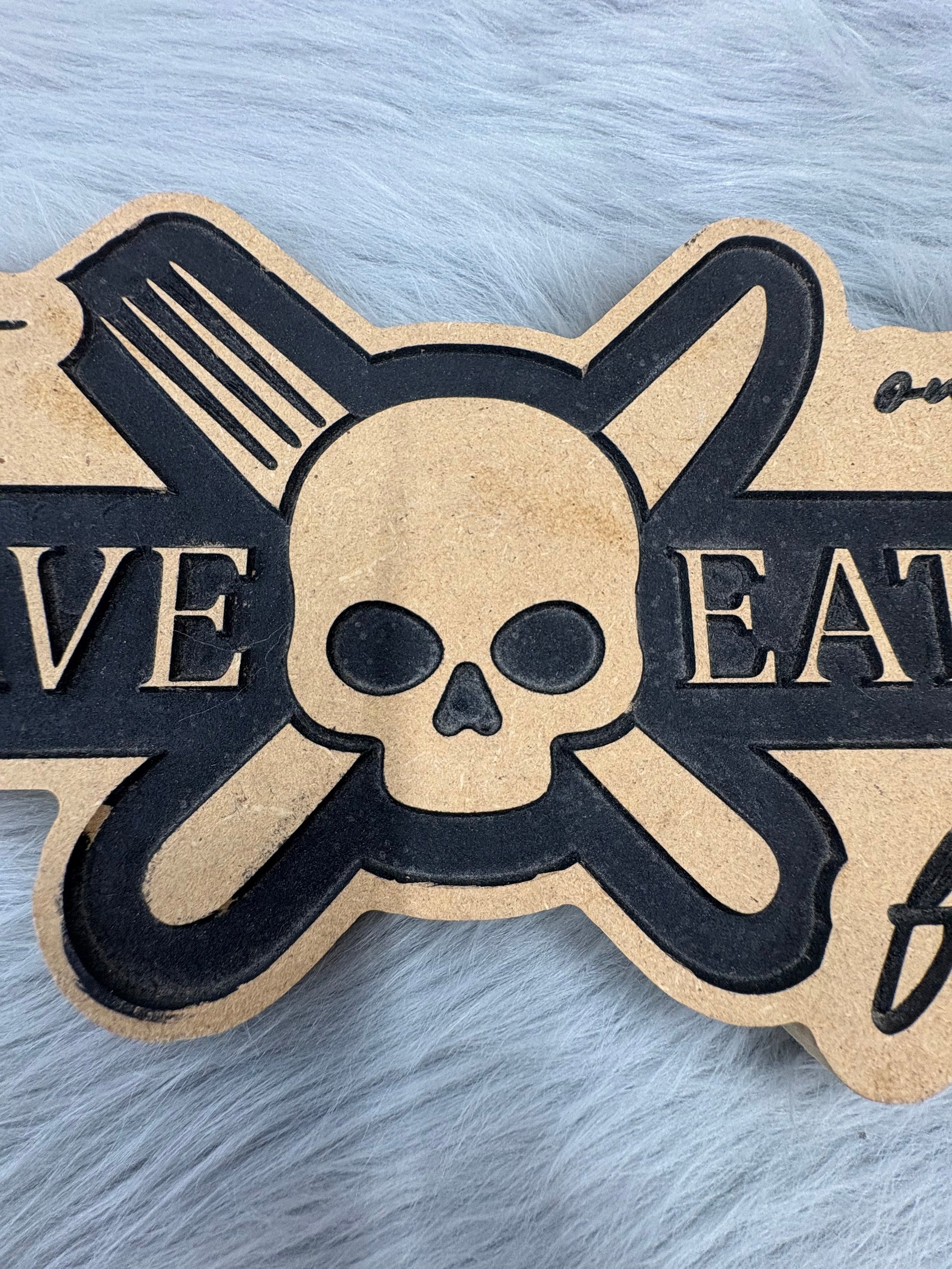 CNC Engraved Kitchen Sign – “Welcome to Our Kitchen: Many Have Eaten Here, Few Have Died” with Skull & Crossbones | Rustic Black & Wood Look | 9.5” x 16” | $30