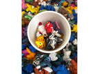 Small white bucket filled with colorful miniature figures surrounded by more figures on a multicolored background