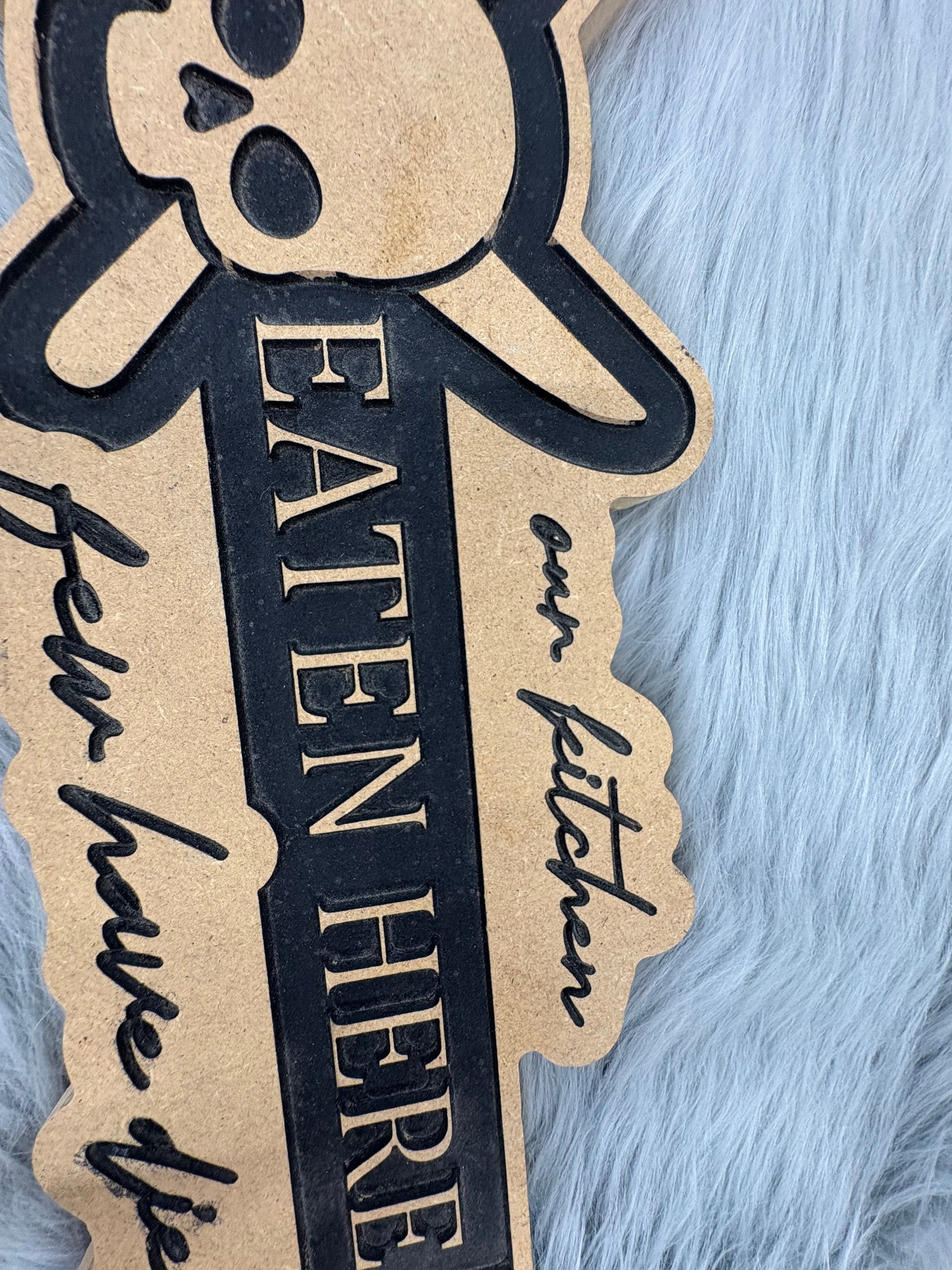 CNC Engraved Kitchen Sign – “Welcome to Our Kitchen: Many Have Eaten Here, Few Have Died” with Skull & Crossbones | Rustic Black & Wood Look | 9.5” x 16” | $30